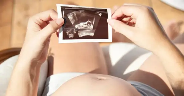 Kobieta trzyma zdjęcie USG, na którym widać zarodek. To nie lewatywa, co to jest? To obraz życia.