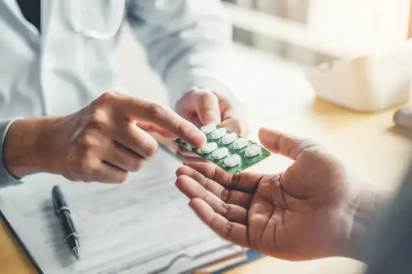 Lekarz podaje pacjentowi blister z tabletkami, być może jest to lek Falcimar.